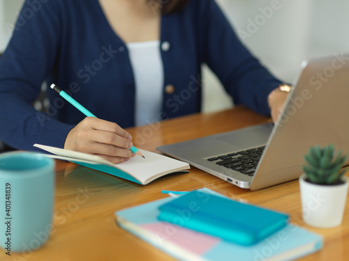Close up view of female university student writing on blank notebook
