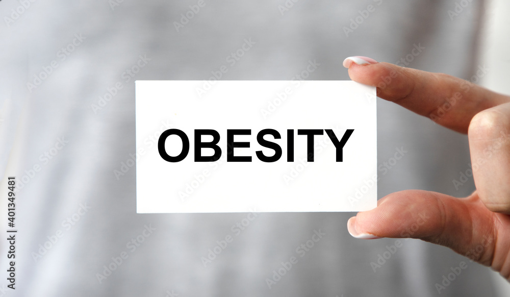 OBESITY. Card with text in hand of Medical Doctor. OBESITY. Card with text in hand of Medical Doctor.