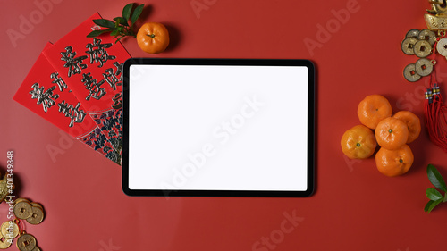 Flat lay a horizontal digital tablet with blank screen and accessories Chinese new year festival on red background. Blank screen for graphics display montage.