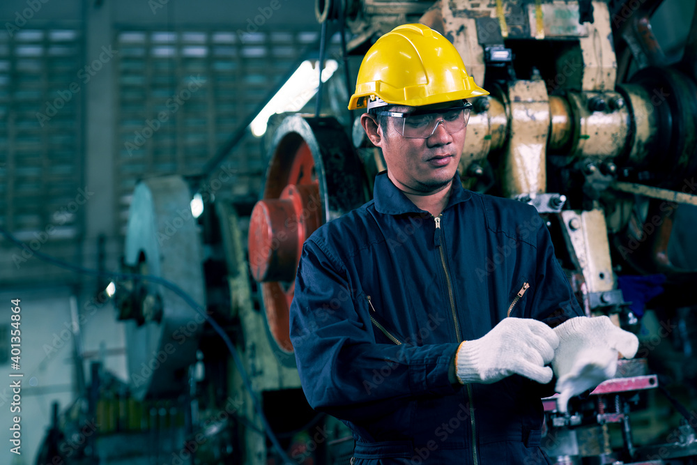 Asian Engineer is wearing white groves and safety helmet in manufactuiring industry Asian Engineer is wearing white groves and safety helmet in manufactuiring industry