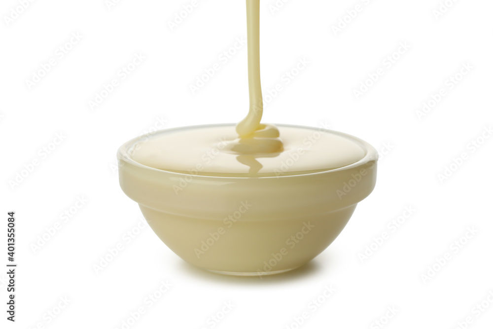 Condensed milk pouring in bowl, isolated on white background Condensed milk pouring in bowl, isolated on white background