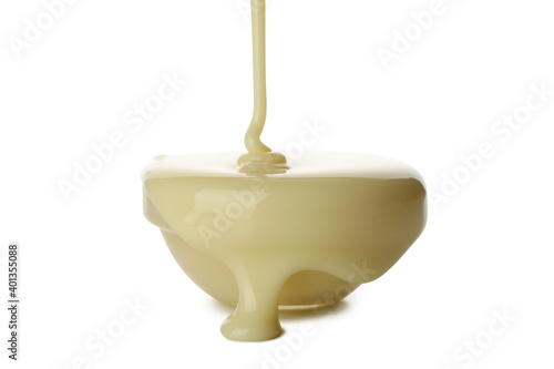 Condensed milk pouring in bowl, isolated on white background photo