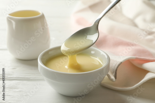Kitchen towel and bowls with condensed milk on wooden background