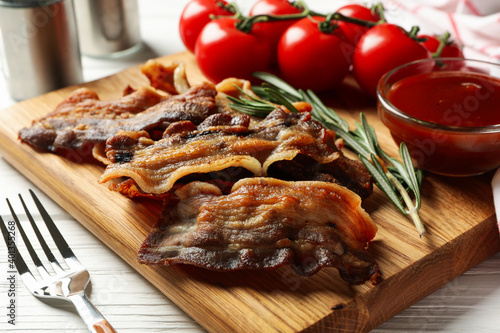 Concept of tasty snack with fried bacon on wooden background