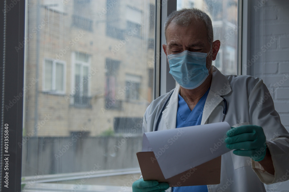 doctor with disposable surgical mask and gloves reviewing medical reports doctor with disposable surgical mask and gloves reviewing medical reports