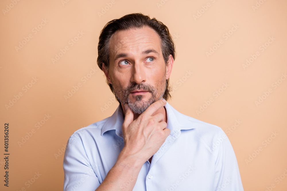 Close-up portrait of minded smart middle aged man overthinking strategy touching chin isolated over beige pastel color background Close-up portrait of minded smart middle aged man overthinking strategy touching chin isolated over beige pastel color background
