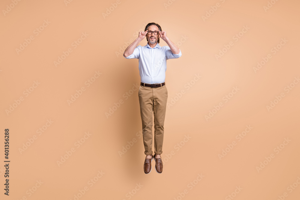 Full length photo of guy jump enjoy wear spectacles shirt trousers footwear isolated beige color background Full length photo of guy jump enjoy wear spectacles shirt trousers footwear isolated beige color background