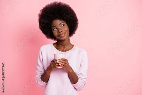 Portrait of pretty dreamy minded cheery wavy-haired girl drinking natural coffee thinking copy space isolated on pink color background