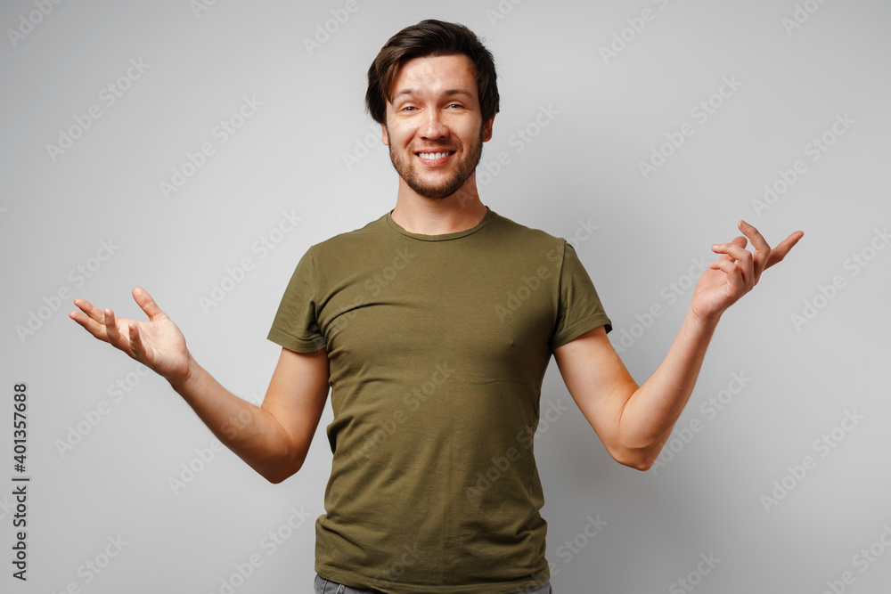 Clueless young man gesturing i don't know against grey background Clueless young man gesturing i don't know against grey background