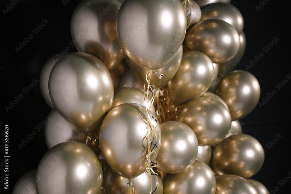 Celebration and party golden christmas baloons with golden ribbons isolated on black background. Event decoration. New year eve. Christmas party. Celebration and party golden christmas baloons with golden ribbons isolated on black background. Event decoration. New year eve. Christmas party.