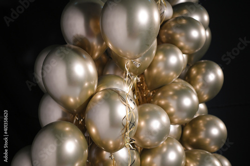 Celebration and party golden christmas baloons with golden ribbons isolated on black background. Event decoration. New year eve. Christmas party.