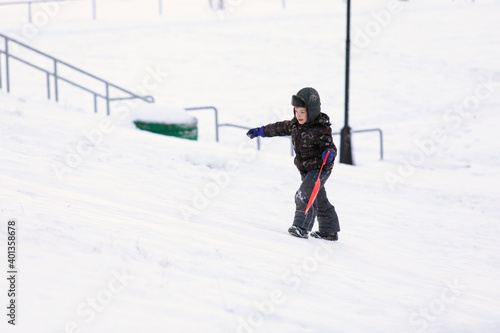 little kid climbs snowy mountain on winter walk.