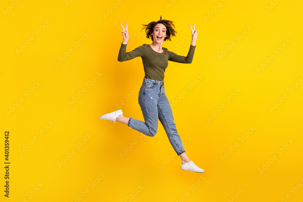Full body photo of energetic girl jump make v-sign wear sweater isolated over shine yellow color background