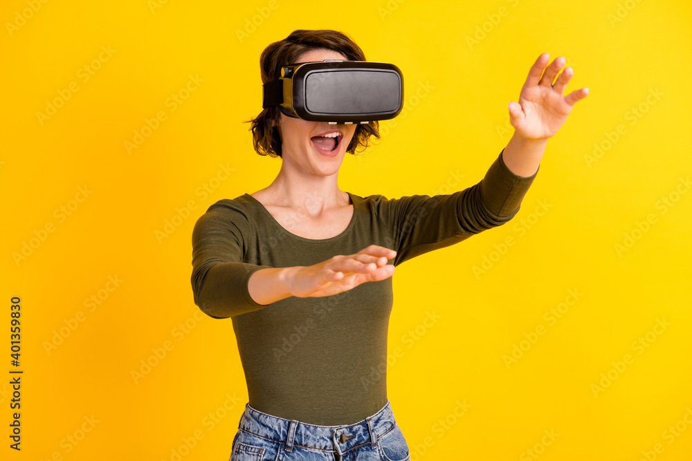 Crazy girl hold hands empty space look in illusion vr goggles wear jeans jumper isolated on bright yellow color background Crazy girl hold hands empty space look in illusion vr goggles wear jeans jumper isolated on bright yellow color background