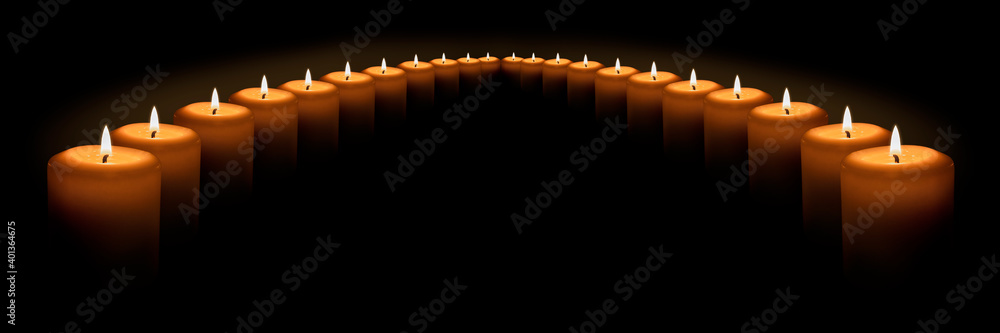 Many burning white candles stand in a semicircle on a black background. Banner with space for text. Many burning white candles stand in a semicircle on a black background. Banner with space for text.