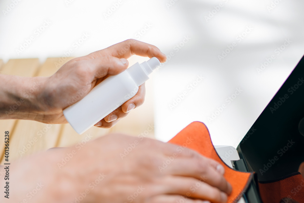close up. man spraying spray on the surface of a laptop close up. man spraying spray on the surface of a laptop