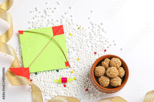 indian festival makar sankranti concept : sesame seed ball or til ke laddo and tilgul in bowl and colorful paper kite on white background photo