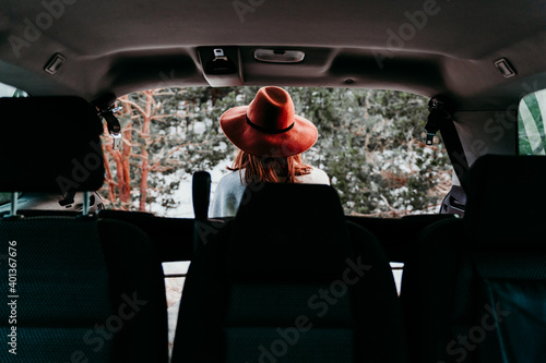 back view from inside a car of young woman outdoors wearing stylish hat. Winter season. snowy mountain background © Eva