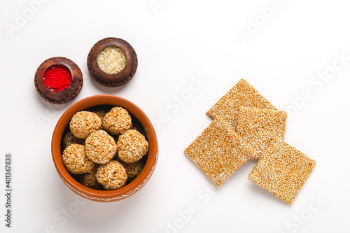 Til chikki and sesame seed ball on white background is an Indian sweet dish made with jaggery and sesame seeds. photo
