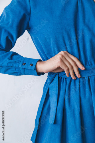 beautiful blue corduroy dress on a girl close-up. Hand on the belt