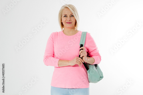 Sporty happy middle age beautiful woman with backpack isolated on white background. Copy space. Mid aged women healthy lifestyle. Menopause, active life. Female going to workout. Healthy aging people © ladyalex