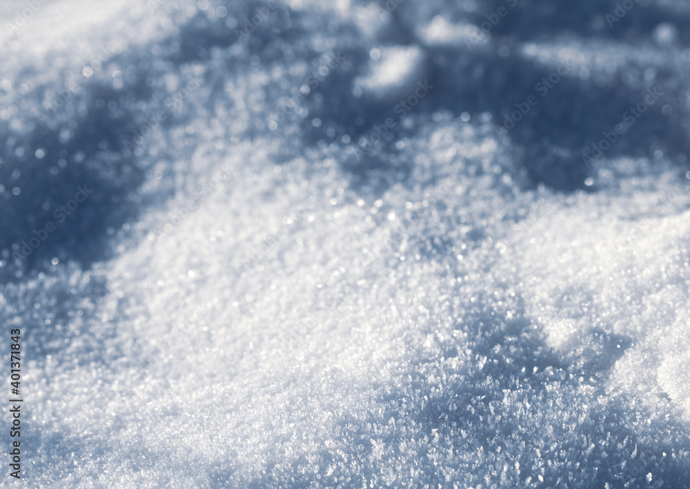 Snowy white background. The texture of the snow. Shiny snow with bokeh and blurred background close-up. White snow-covered field. Macro photo of snow.