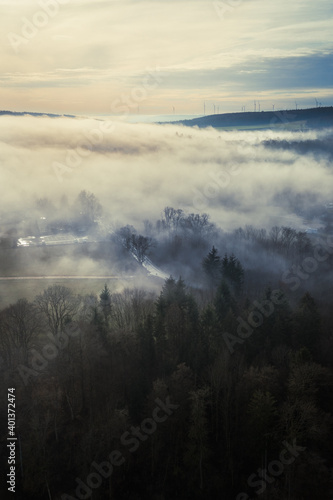 Aerial view of rural landscape and forest in the winter fog, moody atmosphere