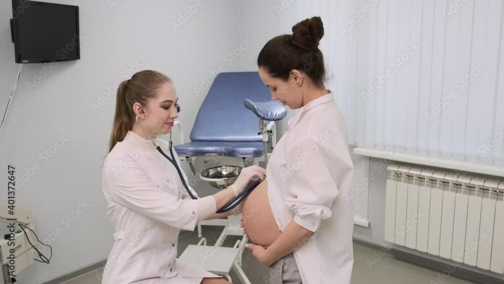 A young girl - a doctor in a white coat examines a pregnant patient in a gynecology office A young girl - a doctor in a white coat examines a pregnant patient in a gynecology office