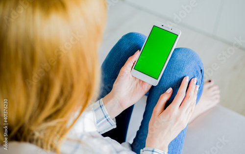 young woman is relaxing on comfortable couch and using smartphone at home