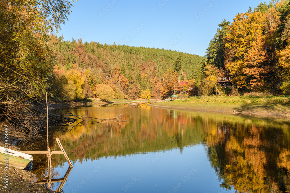 autumn view at river Mze next city Stribro with boat and reflections in water on sunny day