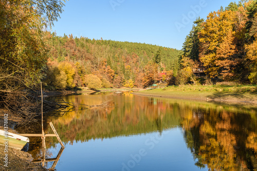 autumn view at river Mze next city Stribro with boat and reflections in water on sunny day