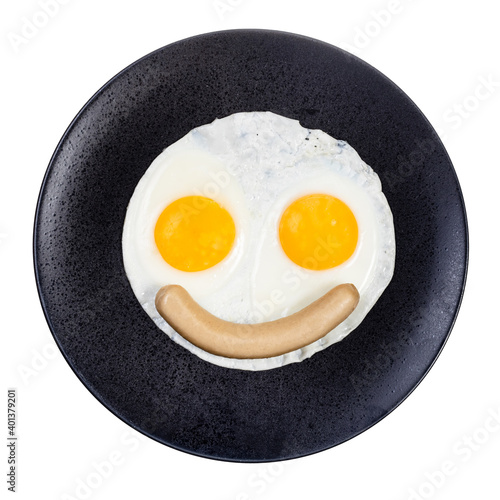 top view of fried eggs and boiled sausage on black plate isolated on white background. Fried eggs like smiling face