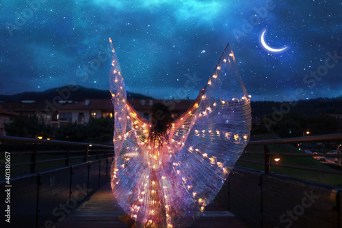 Belly dancer with wings of light under a starry sky