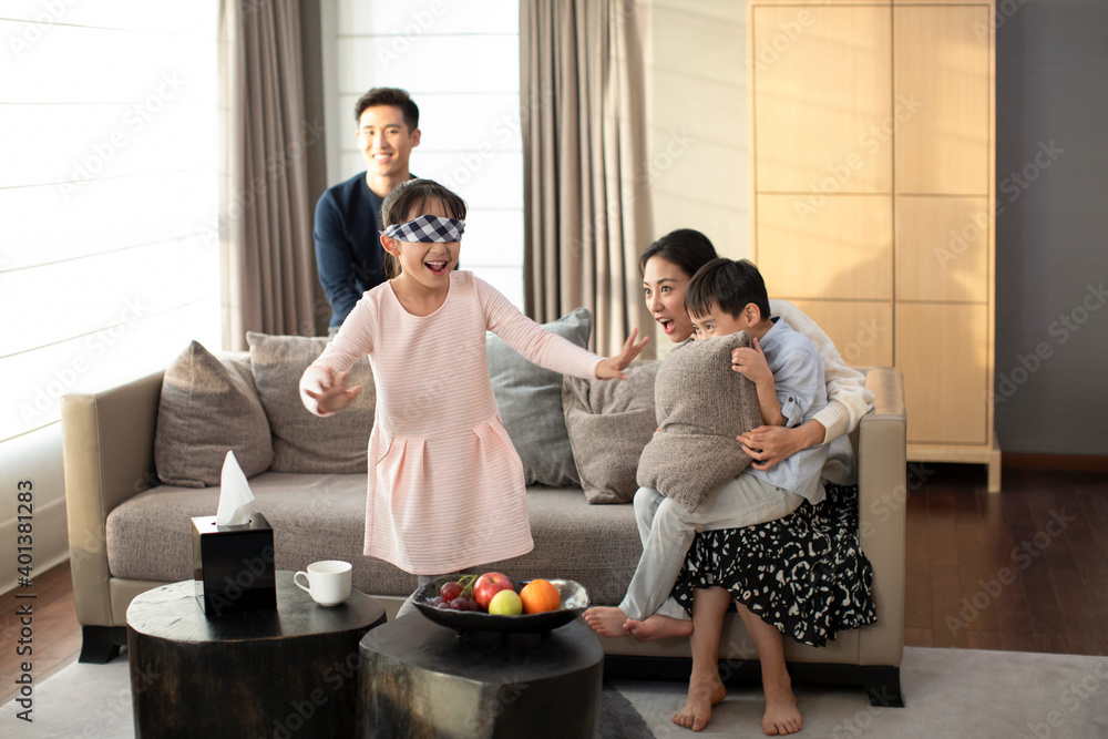 Happy young family playing hide and seek in living room Happy young family playing hide and seek in living room