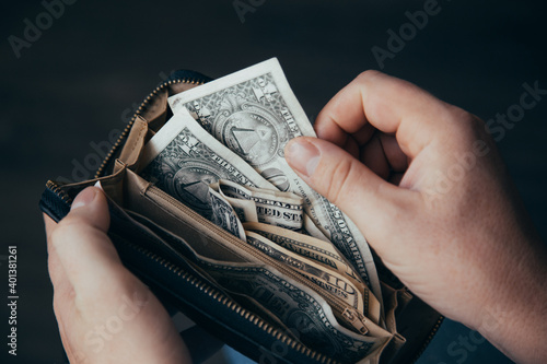 An empty wallet with a small amount of money in the hands of a working man. Poverty concept