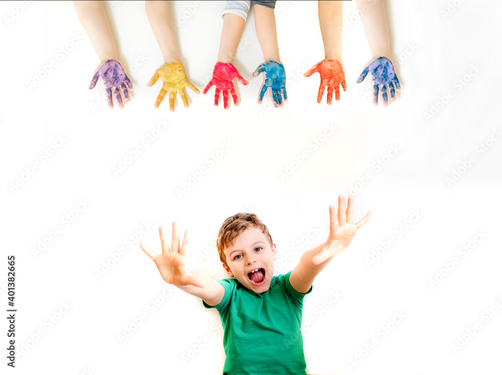boy kid is laughing and shaking hands up on white background near a color painting hands. boy kid is laughing and shaking hands up on white background near a color painting hands.