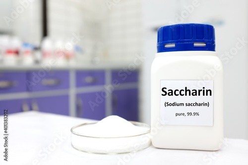 Selective focus of a bottle of pure sodium saccharin artificial sweetener sugar substitute. White laboratory background with copy space. photo