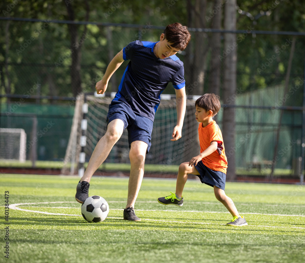 Father and son playing football on field Father and son playing football on field