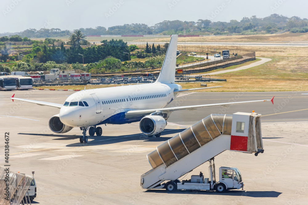 Mobile ladder and an arriving plane with passengers on the apron of the airfield. Mobile ladder and an arriving plane with passengers on the apron of the airfield.
