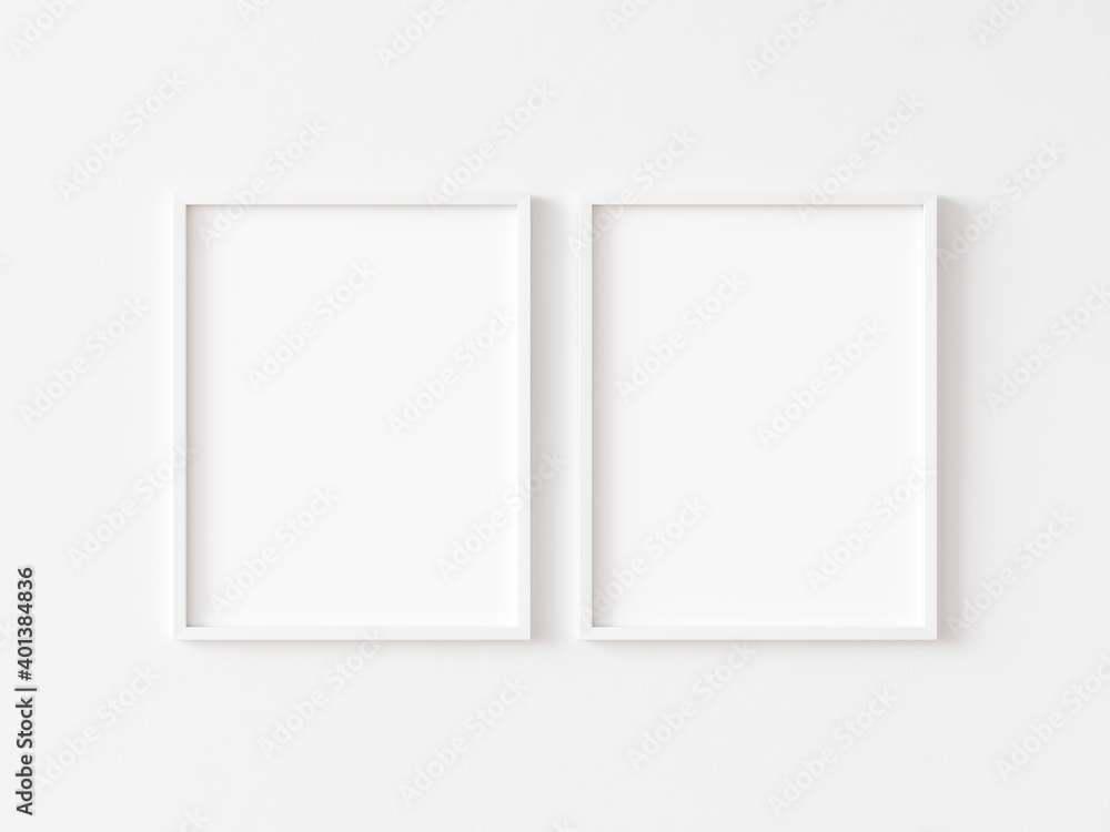Two blank vertically oriented rectangular picture frames with thin white border hanging on white wall. 3D illustration. Two blank vertically oriented rectangular picture frames with thin white border hanging on white wall. 3D illustration.