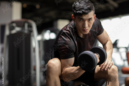 Young man working out with dumbbell at gym photo