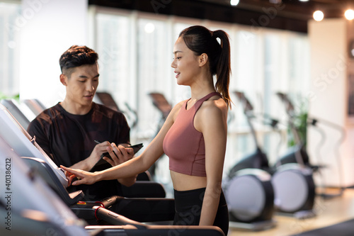 Young woman working out with personal trainer at gym photo