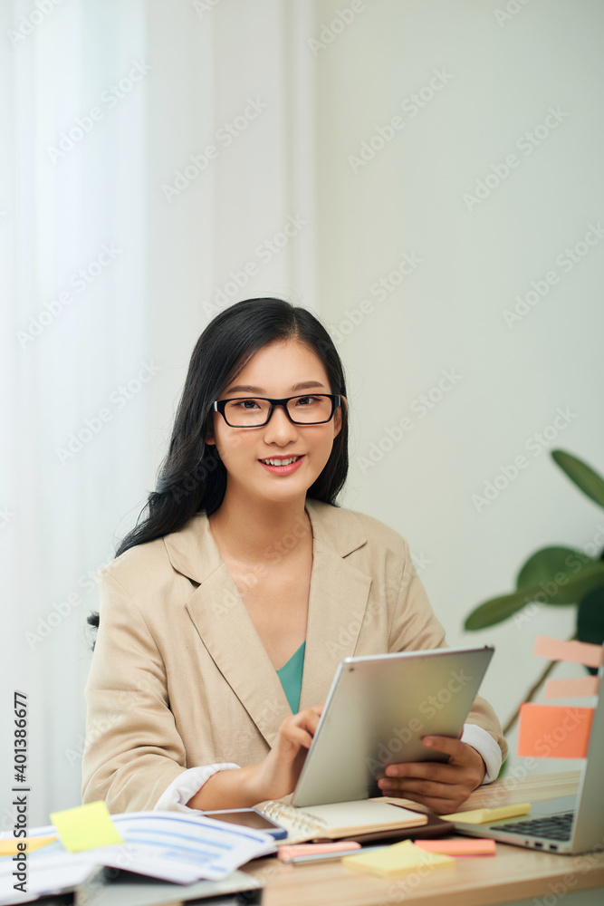 Smiling young African female entrepreneur working online with a digital tablet while sitting at a table in her home office Smiling young African female entrepreneur working online with a digital tablet while sitting at a table in her home office