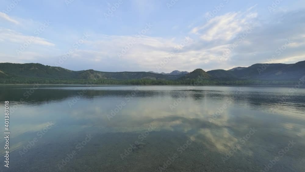 Beautiful clear lake surrounded by mountains. Summer scenery on a sunny day. Clear water with a reflection of clouds. 4K. Beautiful clear lake surrounded by mountains. Summer scenery on a sunny day. Clear water with a reflection of clouds. 4K.