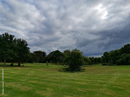 Beautiful morning view of a park with green grass, tall trees and dark cloudy sky, Fagan park, Galston, Sydney, New South Wales, Australia 