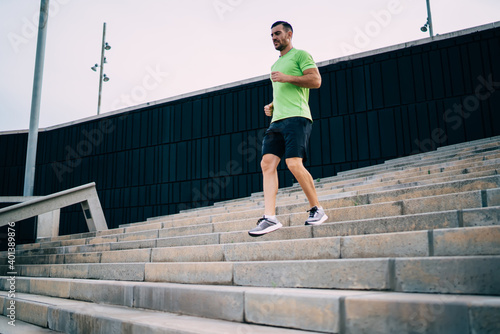 Caucasian male jogger have effort cardio training at urban settings feeling energy and vitality for keeping perfect body shape, determined man running at stairs during morning physical workout