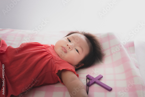 New born baby looking at the cross in her mother hand.