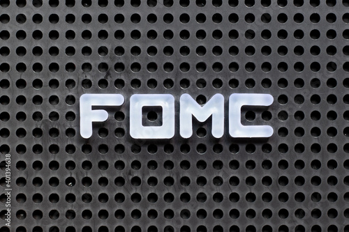 White color letter in word fomc (abbreviation of federal open market committee) on black pegboard background photo