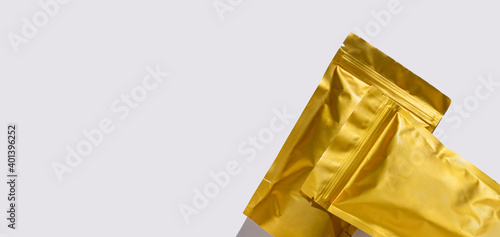 Golden metalized pouch bags mockup with coffee beans top view with harsh shadow isolated on white background. Packaging for food template. Packs with clasps for tea leaves, weight products flat lay. photo