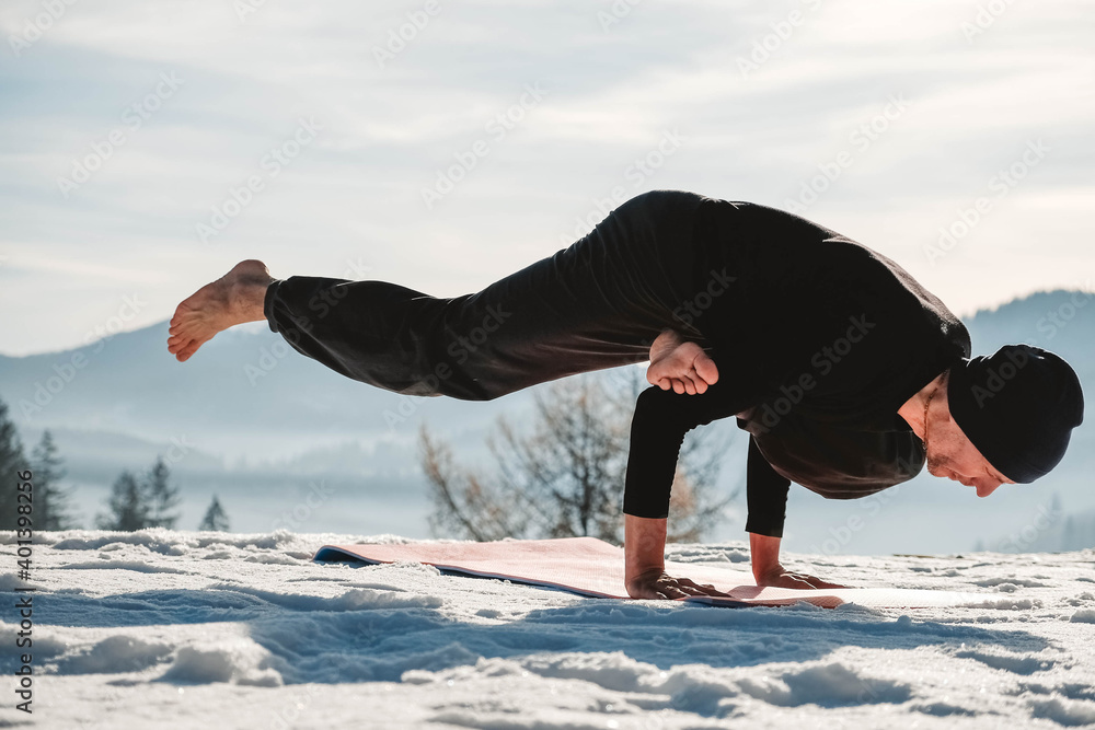 Caucasian senior man doing yoga exercises in front of amazing sunset on the winter mountains. Copy, empty space for text
